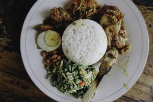 nasi campur ayam betutu. poulet rôti balinais farci de feuilles de manioc. accompagné de riz cuit à la vapeur, sate lilit, jukut antungan, lawar nangka et sambal matah. photo