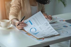 marketing, finance, comptabilité, planification, l'équipe d'hommes d'affaires et d'économistes féminins utilise des calculatrices et des ordinateurs et des documents graphiques au profit de l'entreprise. photo