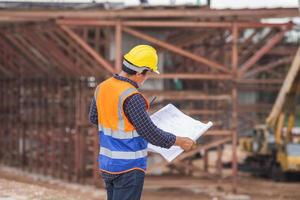 ingénieur en construction asiatique vérifiant le projet sur le chantier, architecte avec des plans sur un chantier de construction, contremaître en casque sur le chantier de construction d'infrastructures photo