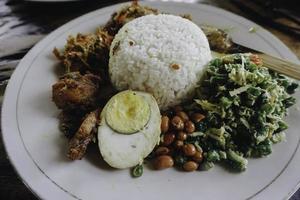 nasi campur ayam betutu. poulet rôti balinais farci de feuilles de manioc. accompagné de riz cuit à la vapeur, sate lilit, jukut antungan, lawar nangka et sambal matah. photo