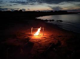 le feu de joie brûle le soir sur la rive du lac photo