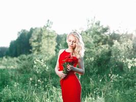 belle jeune femme heureuse avec des fleurs sur un champ, l'été en plein air. photo