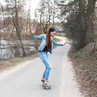 belle fille élégante apprend à faire du skateboard photo