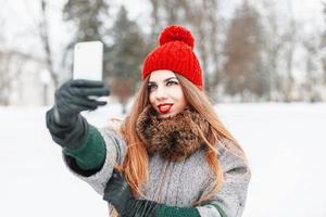 jolie fille s'est photographiée au téléphone sur le fond d'une ville d'hiver photo