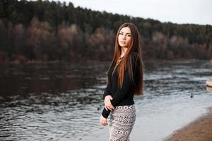 belle fille aux cheveux longs debout près de la rivière par une journée ensoleillée. photo