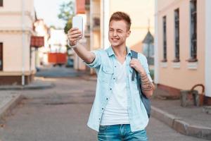 jeune homme se tire une balle au téléphone et fait un clin d'œil photo