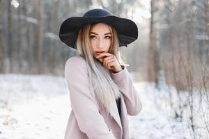 portrait d'une belle jeune femme dans un chapeau noir et un manteau vintage en journée d'hiver fraîche. photo