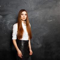 jeune belle fille en robe élégante debout près du mur noir photo