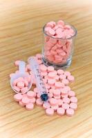 pilules roses et seringue sur table pour concept de soins de santé photo