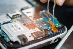 technicien réparant l'intérieur du téléphone portable en fer à souder. circuit intégré. le concept de données, de matériel, de technologie. photo