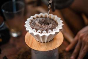 café goutte à goutte, barista versant de l'eau sur du café moulu avec filtre photo