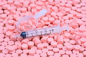 seringue et cuillère sur pilules roses pour concept de soins de santé photo