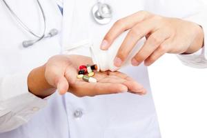 Médecin de sexe masculin asiatique avec des pilules et une bouteille de pharmacie
