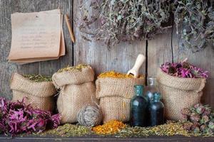 herbes médicinales dans des sacs en toile de jute près d'un mur en bois. photo