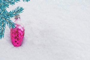 carte de Noël. branche de pin et jouets sur fond de neige blanche. photo