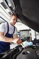 mécanicien au travail, vérification du niveau d'huile sur le moteur d'une voiture