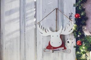 Jouet en bois wapiti orignal patins dans un costume de père noël accroché sur un mur entouré de branches de sapin photo