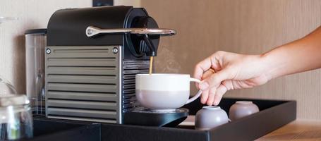 faire de l'espresso à la main par une machine à café avec des capsules sur une table en bois photo