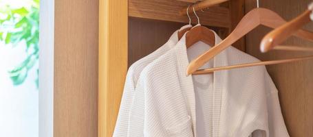 peignoir blanc propre suspendu dans une armoire en bois dans un hôtel de luxe ou à la maison. concept de détente et de voyage