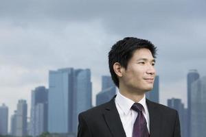 homme d'affaires asiatique heureux devant la ville. photo