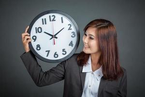 femme d'affaires asiatique montrer une horloge sur son épaule et sourire photo