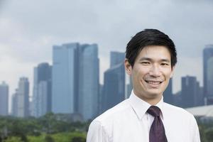 homme d'affaires asiatique heureux devant la ville. photo
