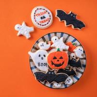 vue de dessus des biscuits au sucre glace décorés de fête d'halloween sur fond orange. photo