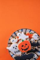 vue de dessus des biscuits au sucre glace décorés de fête d'halloween sur fond orange. photo