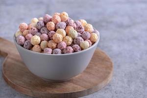 des boules de maïs céréales colorées mélangent des bonbons dans un bol sur fond de ciment gris. photo