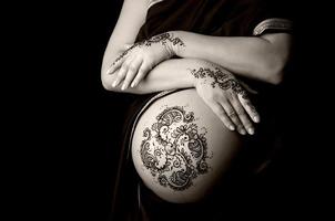 tatouage au henné sur le ventre et les mains d'une femme enceinte photo