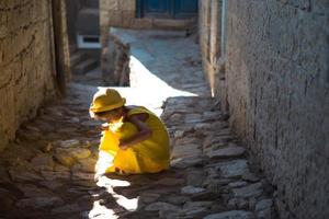 une touriste portant un chapeau jaune et une robe d'été se promène dans la rue de la vieille ville en pierre avec une forteresse. visite guidée. l'enfant s'est perdu, cherchant ses parents photo