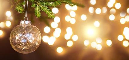 boule de noël dorée sur une branche vivante d'un sapin avec des lumières dorées de guirlandes en défocalisation. nouvel an, noël, fond de vacances, bokeh, espace de copie photo