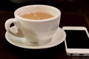 tasse de thé vert et téléphone blanc sur la table photo