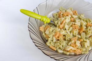 trois pâtes colorées pour les enfants dans une assiette avec une drôle de cuillère photo