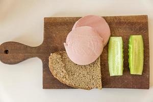 pain de seigle, concombre et saucisse sur un bureau en bois marron photo