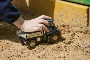 un garçon joue dans un camion dans un bac à sable photo