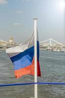 le drapeau national de la russie flotte sur le bateau sur fond de ville de moscou. photo