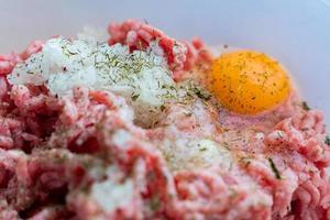 viande hachée dans un bol avec œuf cru, épices et oignon haché pour la cuisson des escalopes, mise au point sélective photo