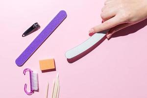 la femme aligne ses ongles avec une lime à ongles. alignement du bord de l'ongle. manucure à la maison pour vous-même. la main d'une femme avec des ongles naturels sains. procédure de soin des ongles. vue de dessus. photo