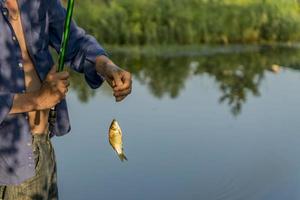 un homme cache du poisson dans l'étang photo