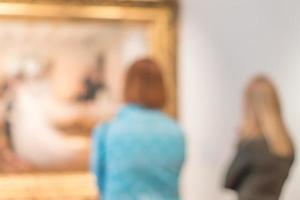 deux femmes regardent des peintures dans un musée, image défocalisée. photo