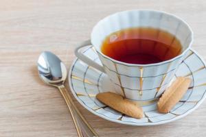 tasse de thé noir avec un délicieux biscuit croquant sur une table en bois photo