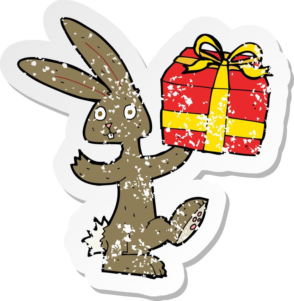 autocollant rétro en détresse d'un lapin de dessin animé avec un cadeau de noël vecteur