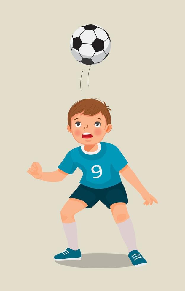 mignon petit garçon jouant au football s'entraînant à frapper le football avec sa tête vecteur