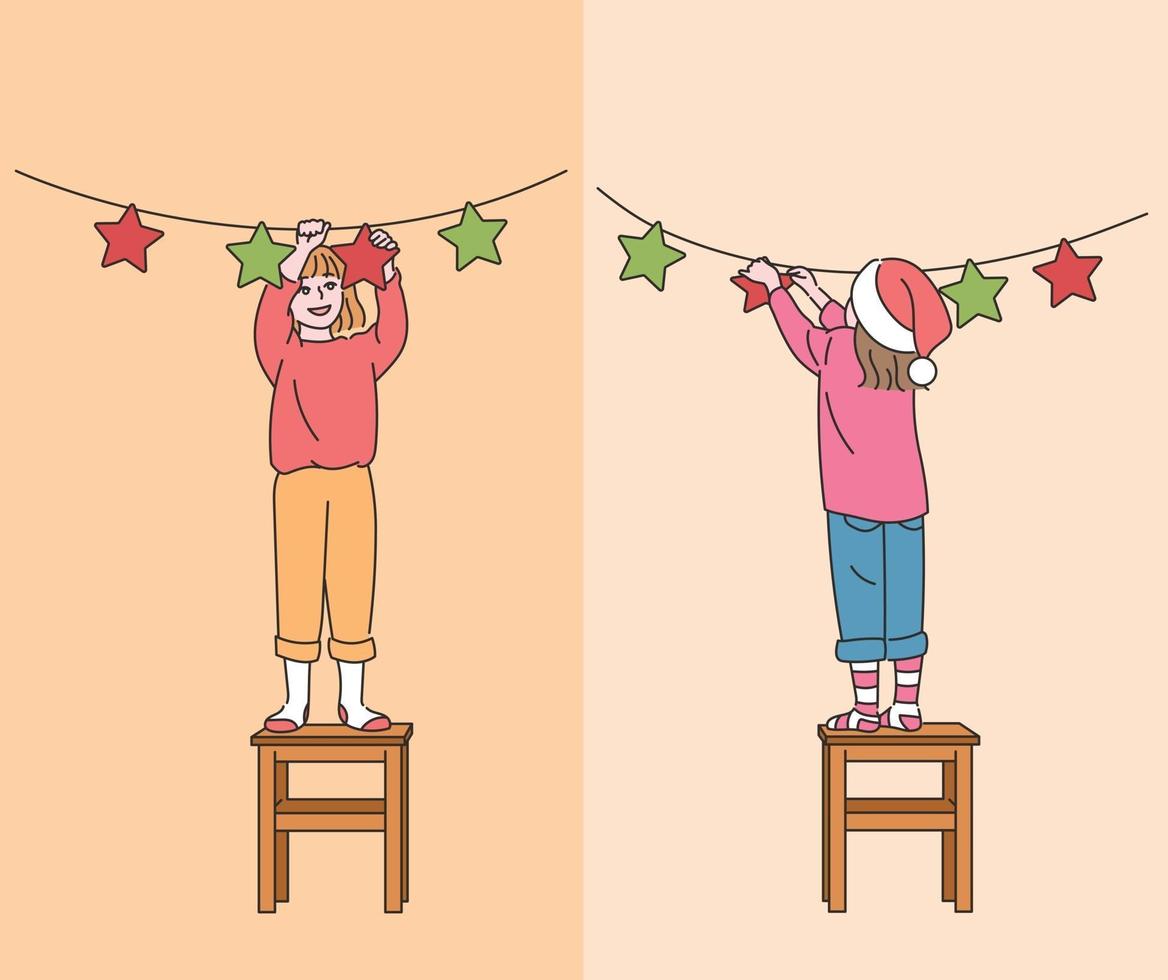 des enfants mignons sont debout sur les chaises et les décorent pour Noël. illustrations de conception de vecteur de style dessiné à la main.