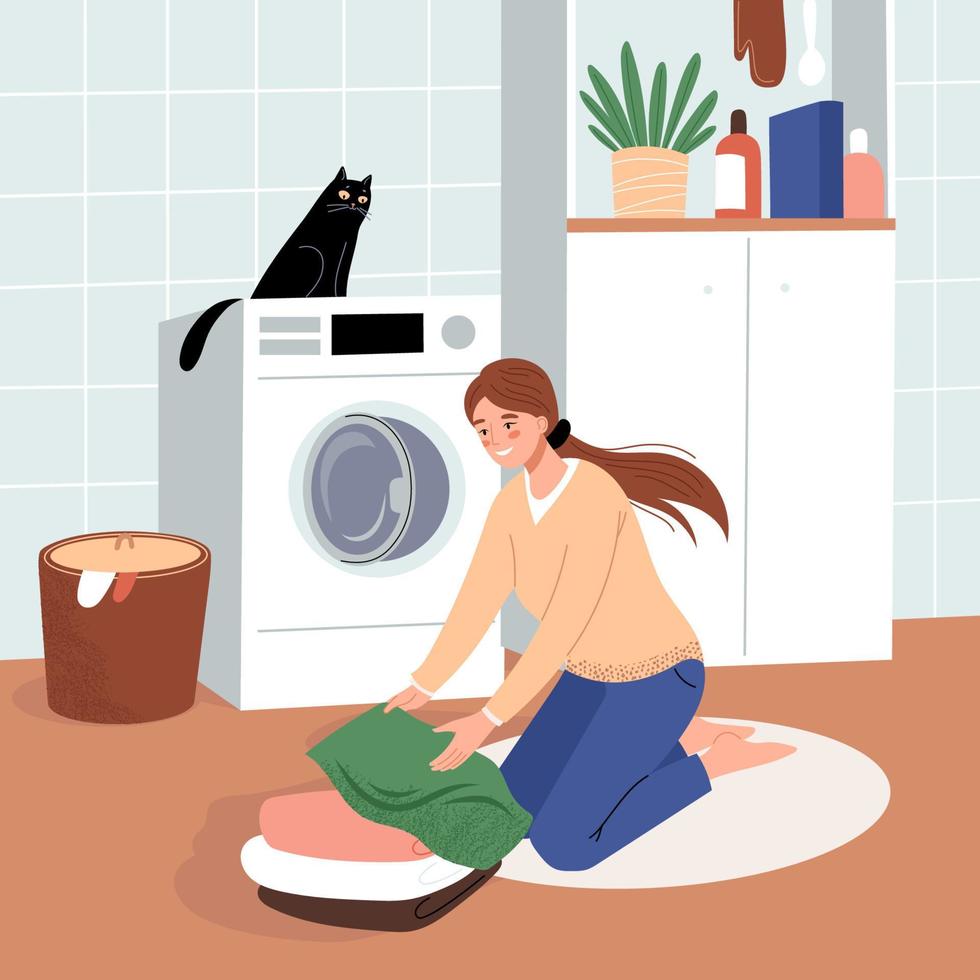 une femme heureuse dans la blanchisserie plie du linge propre. Machine à laver. le chat est assis sur la machine à laver vecteur