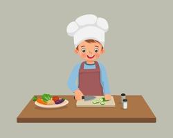 mignon petit garçon chef cuisinant des repas coupant des légumes de concombre en tranches avec un couteau dans la cuisine vecteur