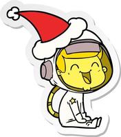 dessin animé autocollant heureux d'un astronaute portant un bonnet de noel vecteur