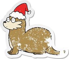 dessin animé autocollant en détresse d'une loutre portant un bonnet de noel vecteur