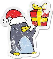 autocollant en détresse d'un pingouin de dessin animé avec un cadeau de Noël vecteur